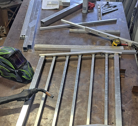 A table cluttered with tools and metal bars, showcasing Oceanside Welding metal shop Miami FL workspace for fabrication