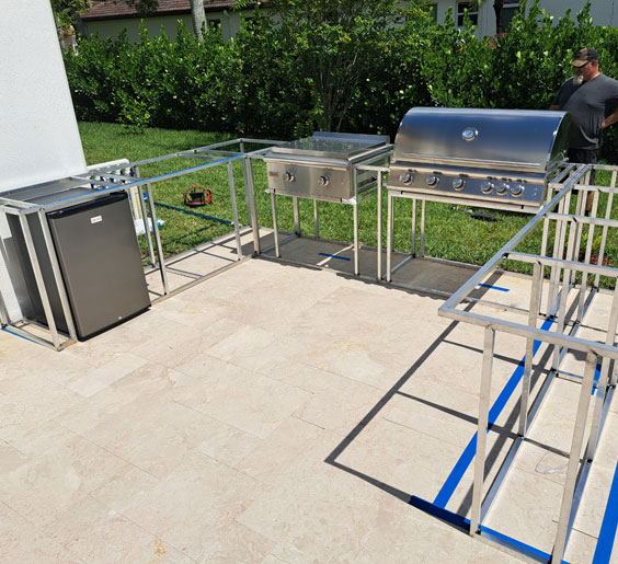 A backyard featuring a metal grilling station with a mini fridge.