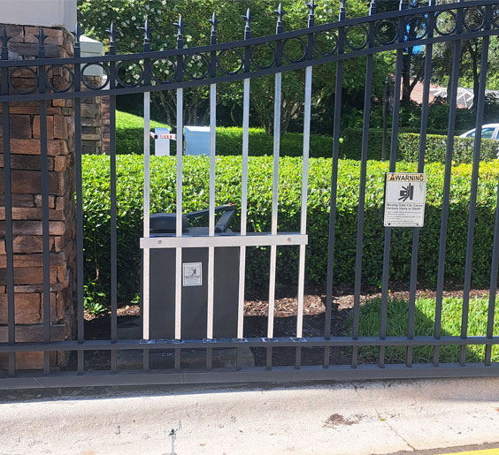 A black aluminum fence Miami gate with a warning signage