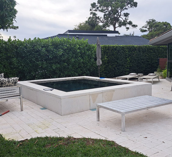 A patio featuring a pool alongside a metal table and metal benches in Davie, FL.